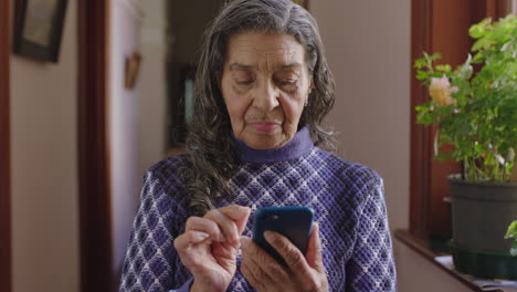 Retrato-De-Una-Anciana-India-Enviando-Mensajes-De-Texto-Navegando-Usando-Una-Aplicación-Para-Teléfonos-Inteligentes-En-El-Pasillo-De-Una-Casa-De-Retiro