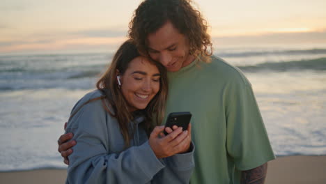 couple enjoying sunset at the beach with their phone