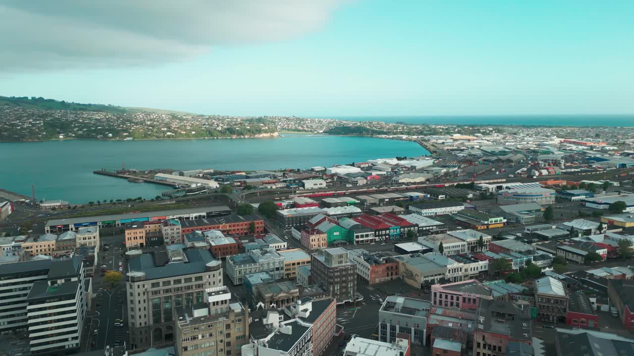 Drone fly over of Dunedin city with lake, mountains, and ocean in background
