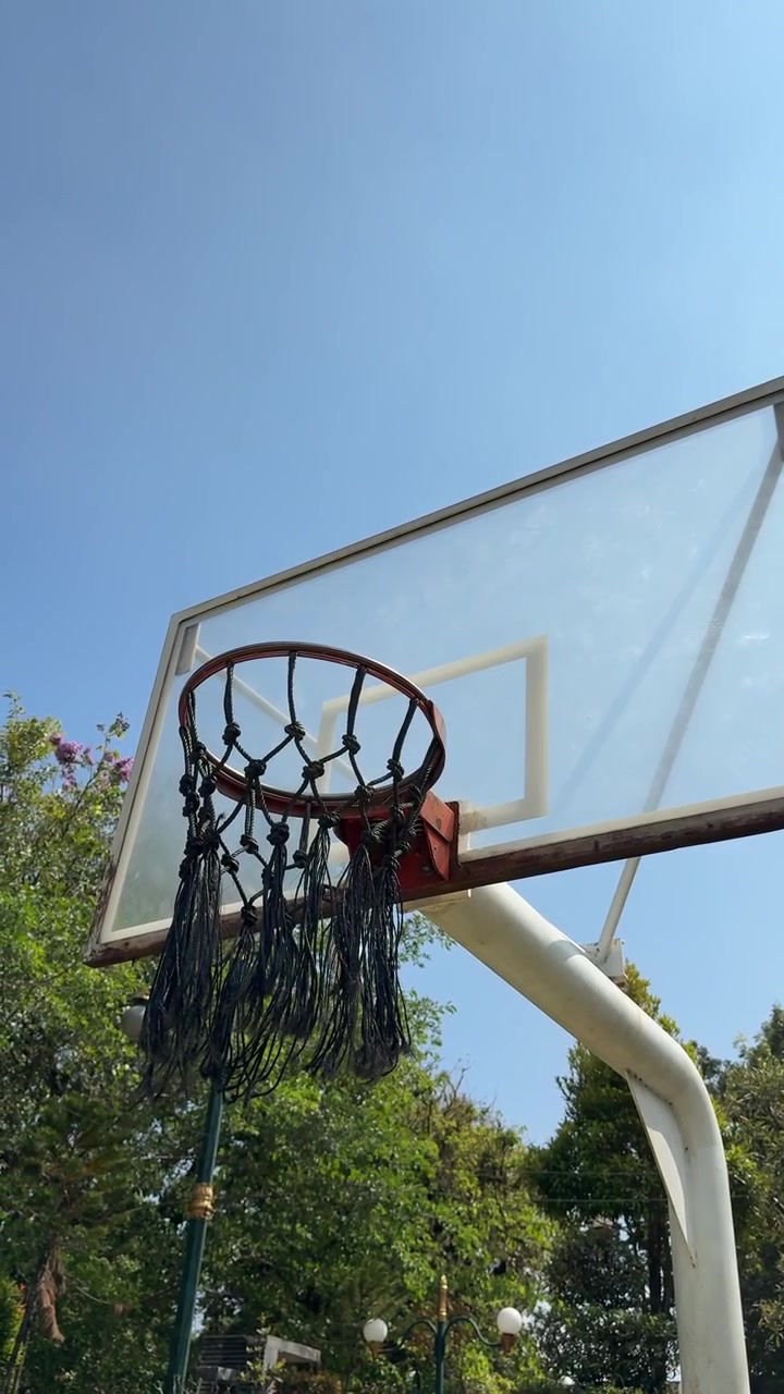 Canestro da basket all'aperto contro un cielo azzurro limpido.