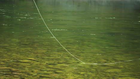 Línea-De-Pesca-Lanzada-Varias-Veces-Al-Arroyo-Con-Agua-Verde-Clara,-Nadie