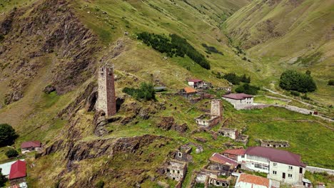 Historic tower in Kazbegi valley rural rugged valley. Drone aerial fly through t old stone buildings in rocky village landscape