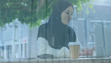 animation of financial data processing over biracial woman in hijab using laptop in city