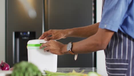 de manos de hombre afroamericano compostando residuos en la cocina