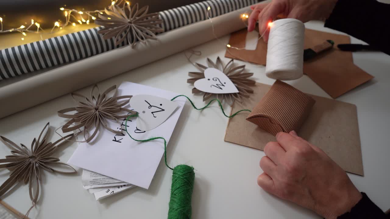 Gift wrapping a brown cardboard pillow box for Christmas by caucasian woman
