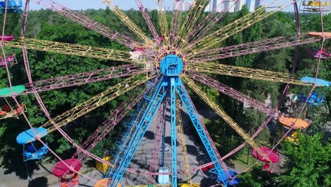 underside or side view from ground of a ferris wheel over blue sky. bright and colorful fragment of moving round ferris wheel in summer.