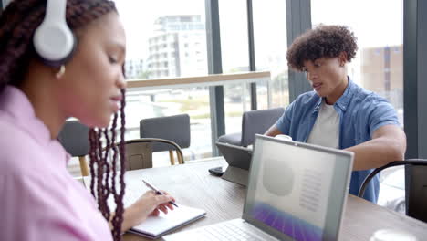 Working in office, colleagues using laptops and taking notes during meeting