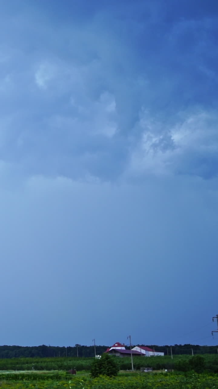 Set of beautiful lightning strikes on blue background. Small electrical lightnings in the sky over the green nature in the evening. Vertical video