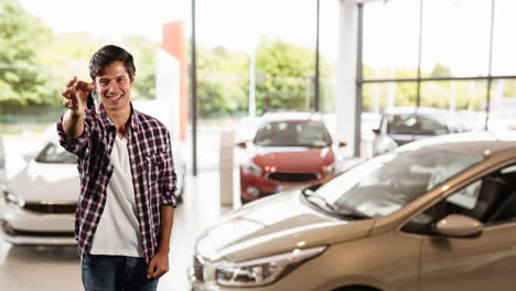 hombre caucásico mostrando las llaves de sus coches en un distribuidor de coches, pareciendo feliz
