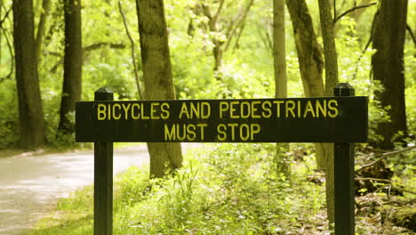 firmar en el bosque que dice que las bicicletas y los peatones deben detenerse cerca