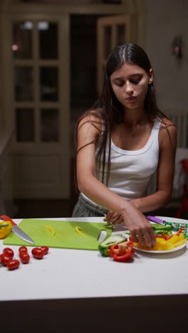 woman preparing a colorful vegetable dish in the kitchen at night