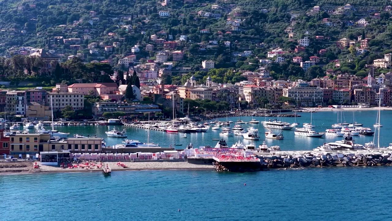 Ampia inquadratura dall'alto di un pittoresco porto italiano con yacht, acqua turchese ed edifici sulla collina
