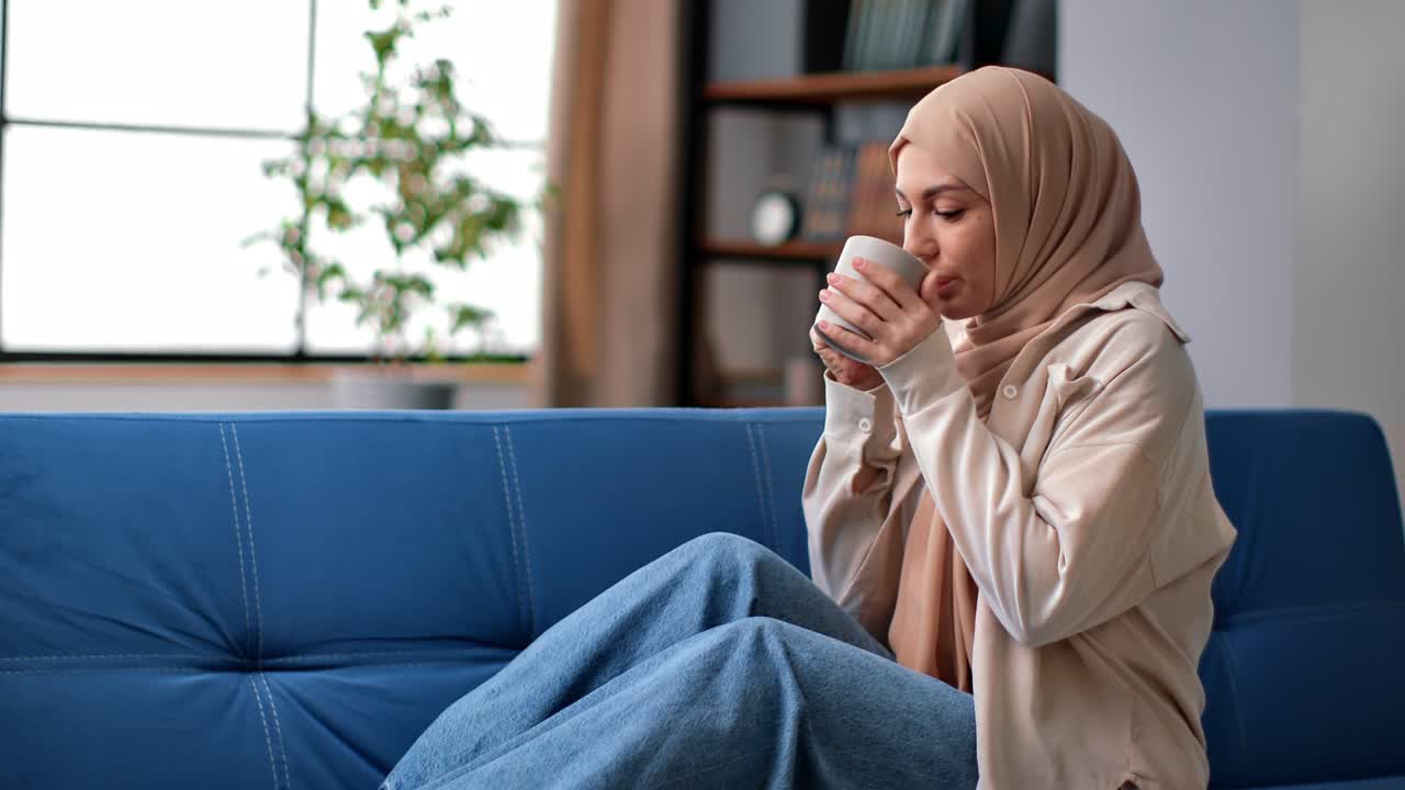 Muslim woman in hijab relaxing drinking cup of hot coffee or tea on ...