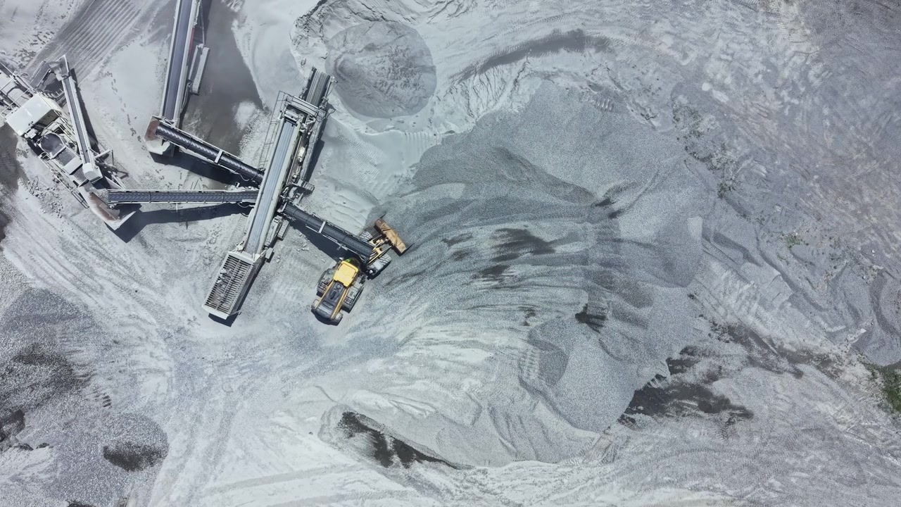 Granite quarry operations take place at a site with machinery moving and processing stone materials during daylight hours