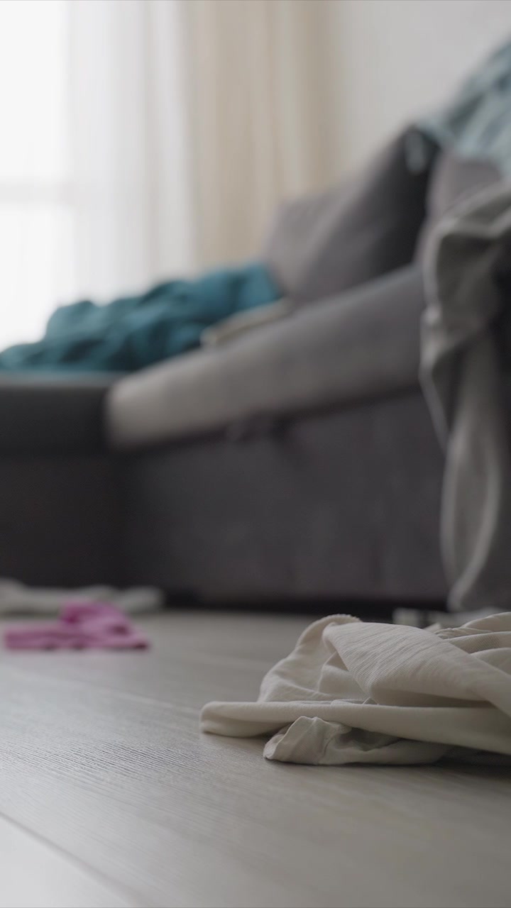 Living room focuses primarily on texture details and composition. gray sofa is visible in soft focus background with blue fabric while white floor takes up most foreground space. Scattered