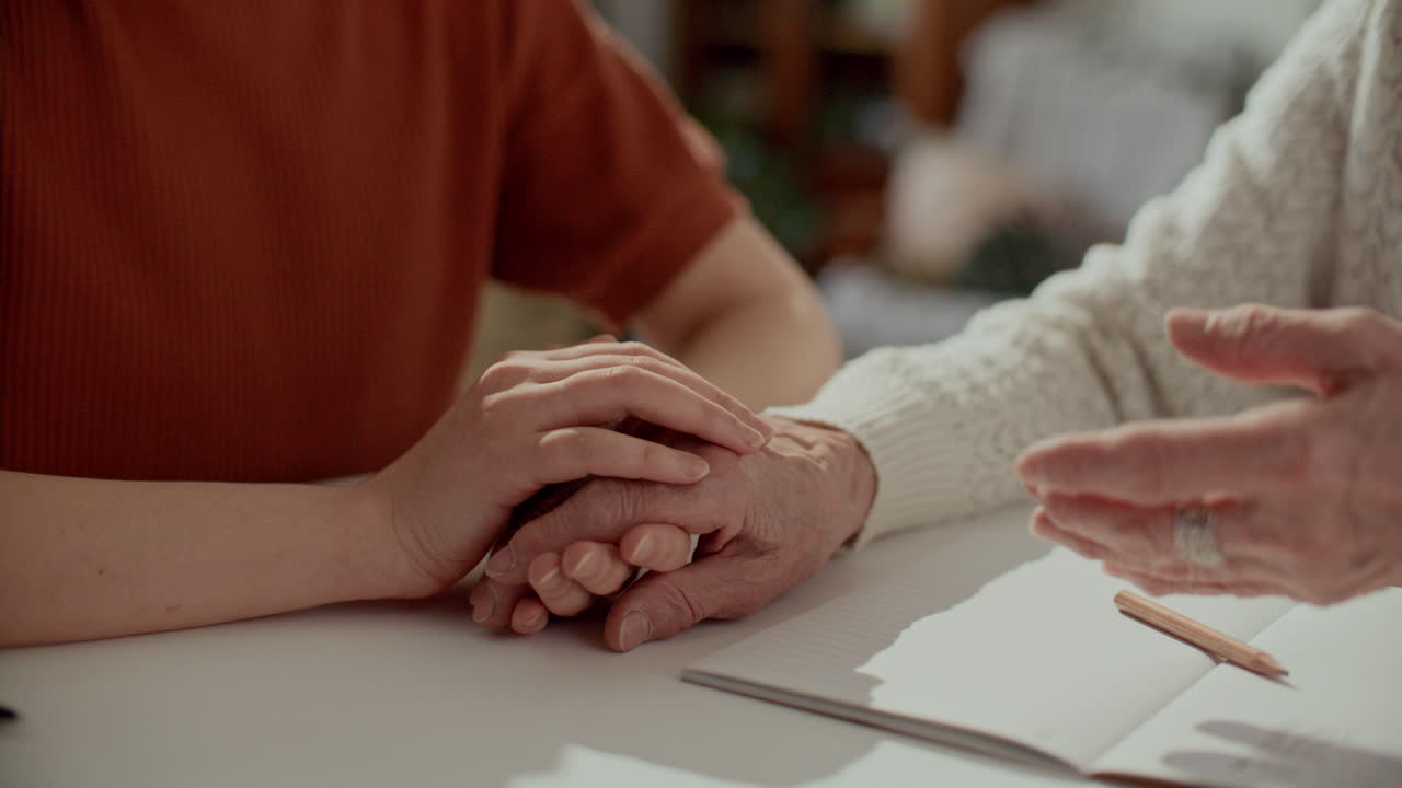 Woman Comforting Elderly Grandmother by Holding Hands during Conversation