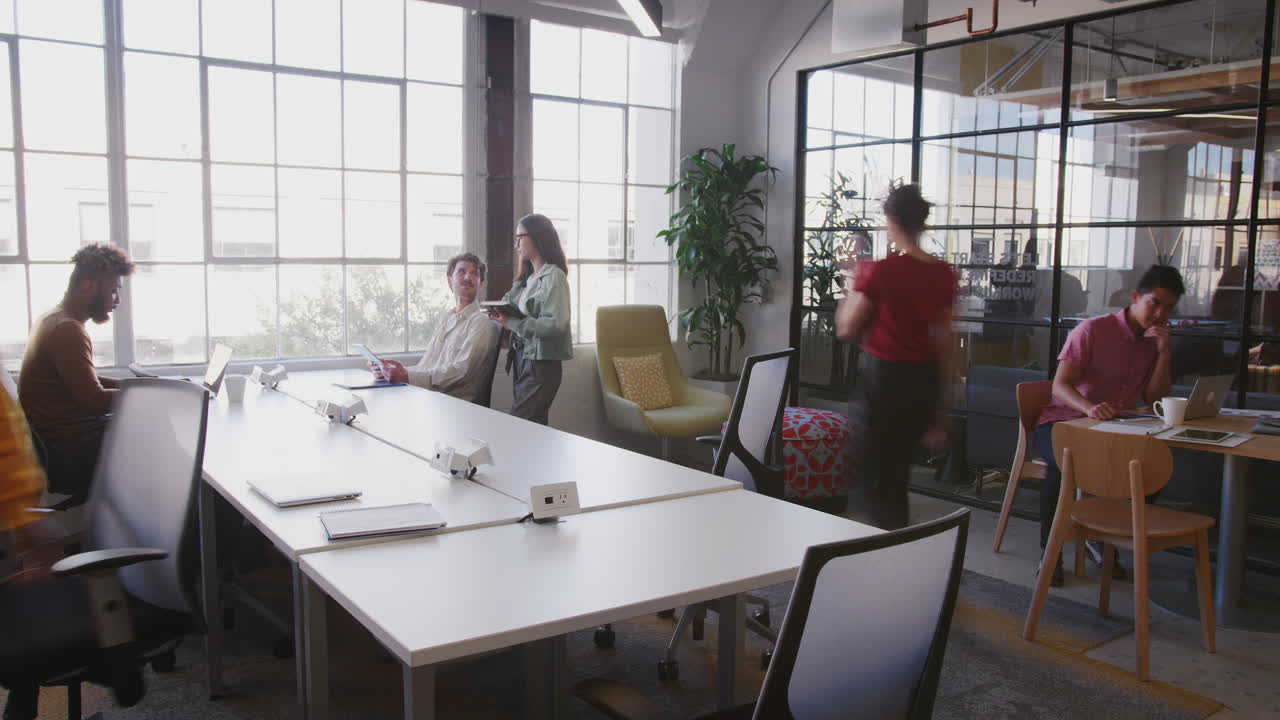 Millennial multi-ethnic colleagues working in a busy open plan creative office, fast motion