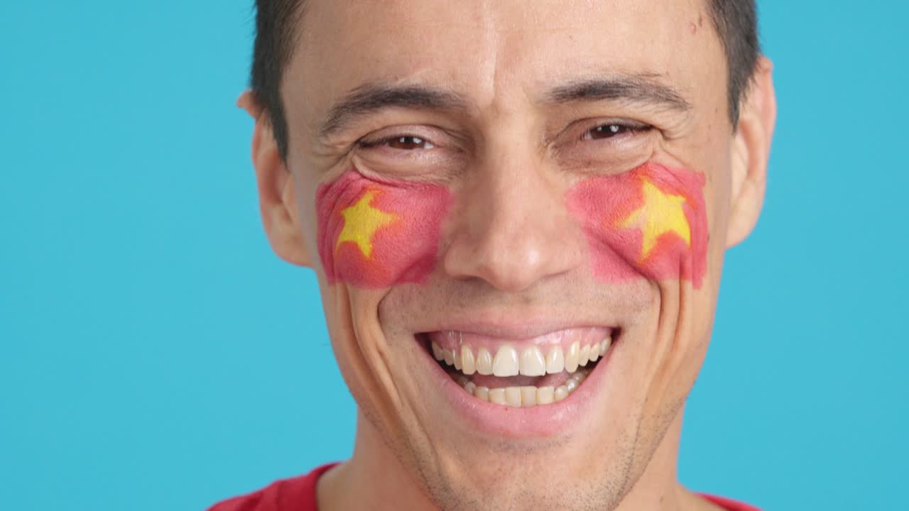Man with a vietnamese flag painted on the face smiling