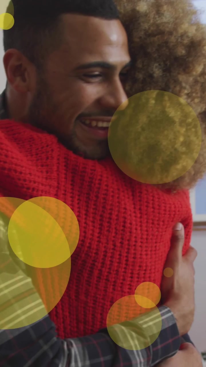 Animação de pontos se movendo sobre um casal afro-americano se abraçando debaixo da árvore de Natal