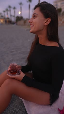 woman enjoying tea at the beach at sunset