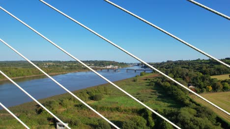 drone looking through suspension cables down river to waterford city ireland on a calm summer evening