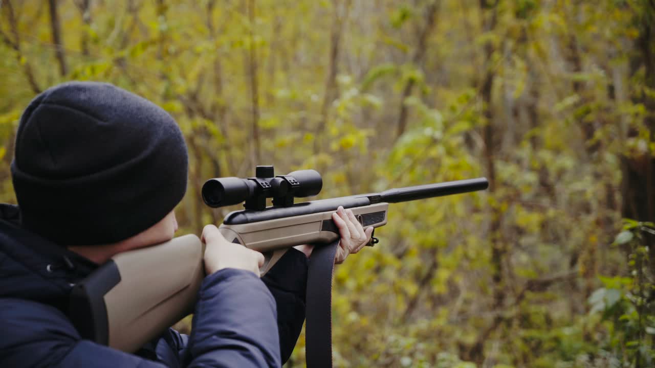 Man aiming with hunting rifle. Hunter man looking through the scope of hunting rifle