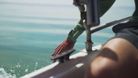 Slow-motion-video-of-a-hand-reaching-out-to-touch-some-splashing-water-from-a-boat-slowly-driving-through-the-water