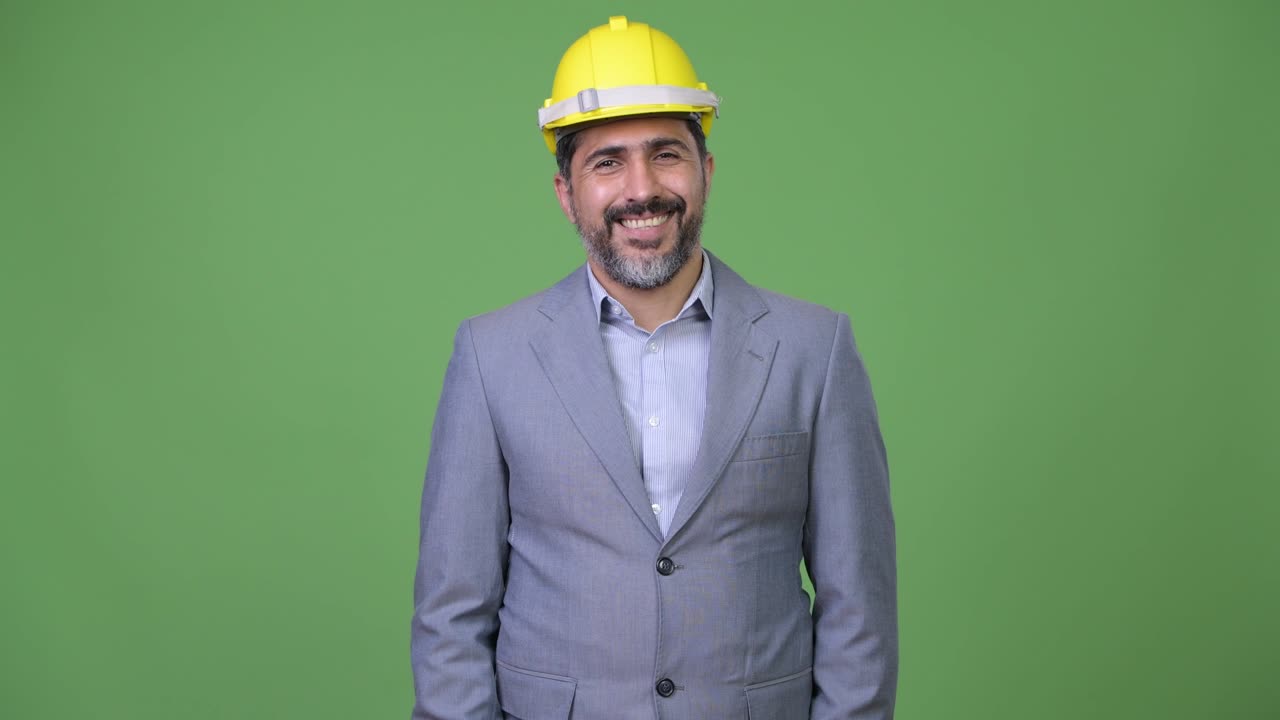 Handsome happy Persian bearded businessman as engineer smiling