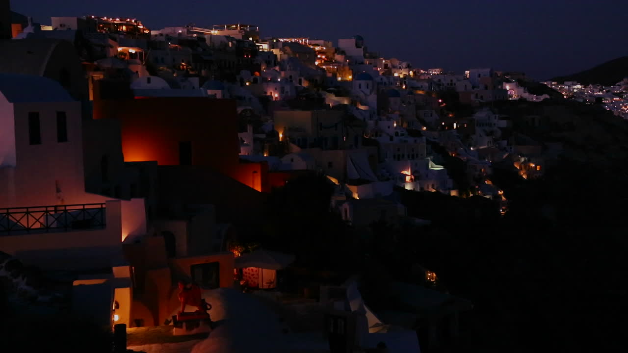 una toma amplia de un pueblo en los acantilados de santorni en las islas griegas por la noche 1