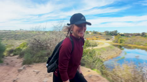 Young-happy-smiling-woman-hiking-with-her-dogs-next-to-a-lake-in-southern-california-on-a-brisk-day-in-December