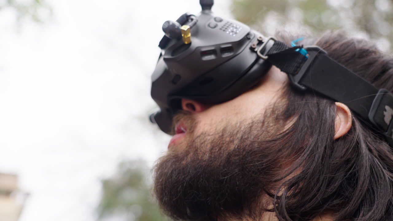 Man with Beard Puts on FPV Goggles and Looks Up