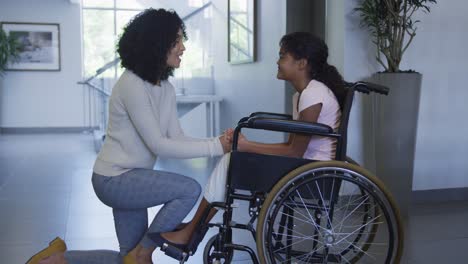 Afroamerikanische-Mutter-Umarmt-Ihre-Tochter,-Die-Im-Krankenhaus-Im-Rollstuhl-Sitzt