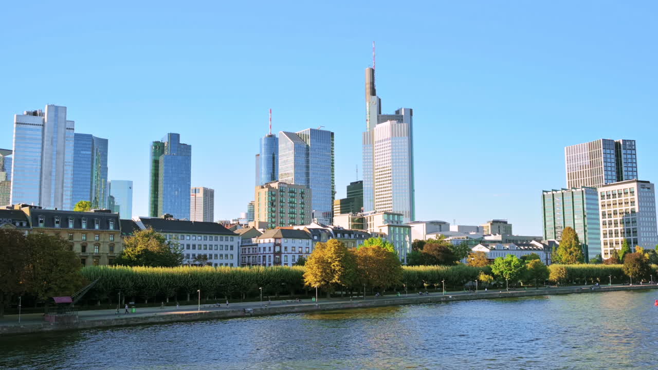 Stadtbild der Frankfurter Innenstadt, Deutschland. Main mit festgemachten Booten, Wolkenkratzer im Hintergrund, andere Gebäude, flanierende Menschen