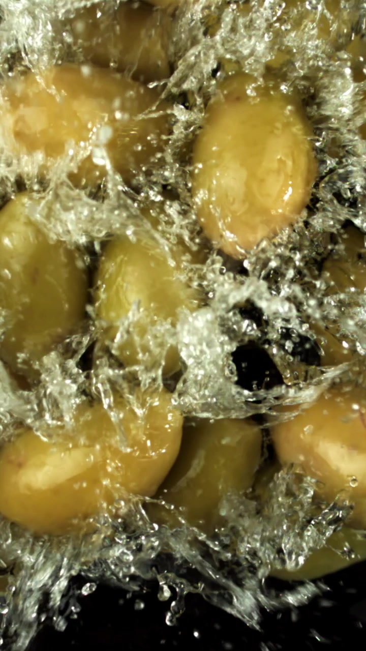 Olive verdi fresche che schizzano nell'acqua al rallentatore