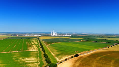 enormous agricultural fields on summer day. the huge pipes of the industrial plant produce smoke. slovakia scenery