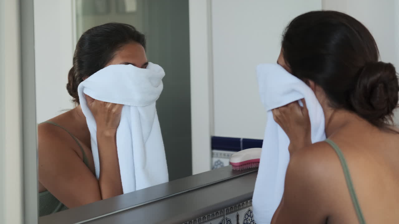mujer secando la cara en el baño