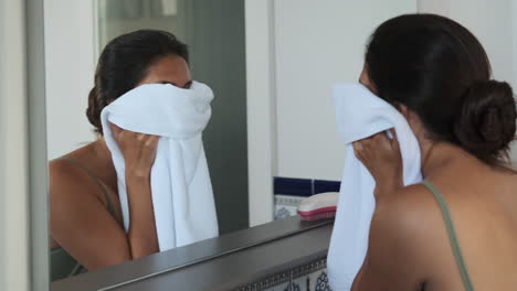 woman drying face in bathroom