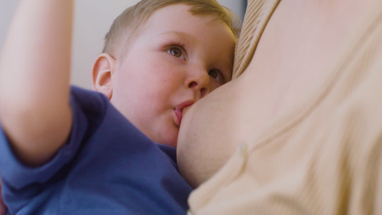 집에서 아기에게 젖을 먹이는 알아볼 수 없는 어머니를 닫습니다