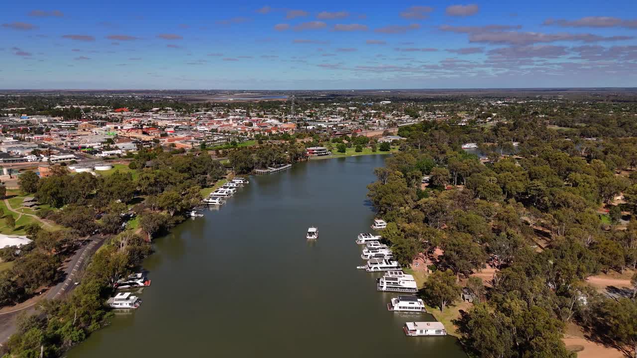 Luftopptak etablerer seg over Milduras elvebredd med båter og grønne forsteder under klar, blå himmel, Australia
