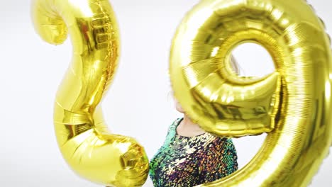 joven con globos dorados construyendo la figura "29"
