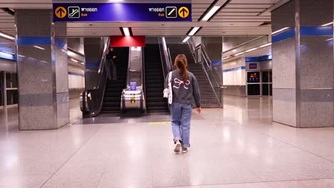 a woman walks towards an escalator