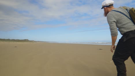 un marinero de 1900 caminando a lo largo de una playa remota con una bolsa de lona en el hombro en australia.