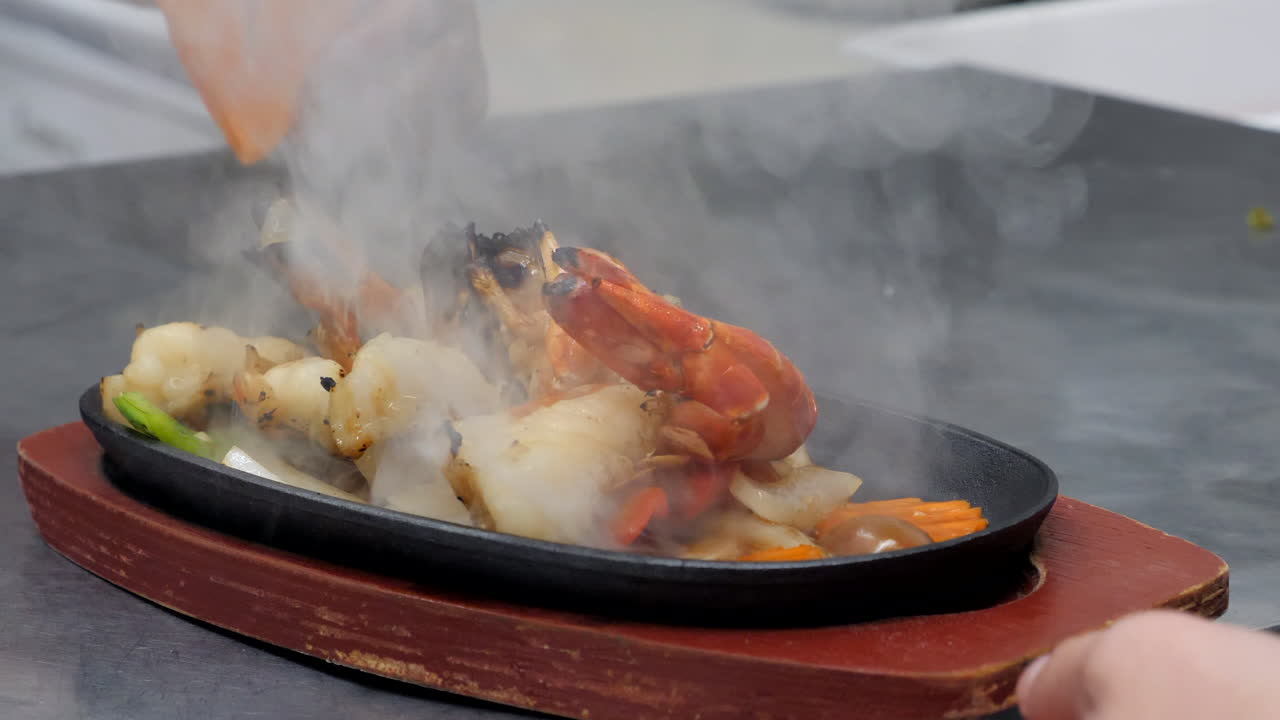 chef de primer plano que sirve gambas de agua dulce a la parrilla en el plato caliente con verduras salteadas