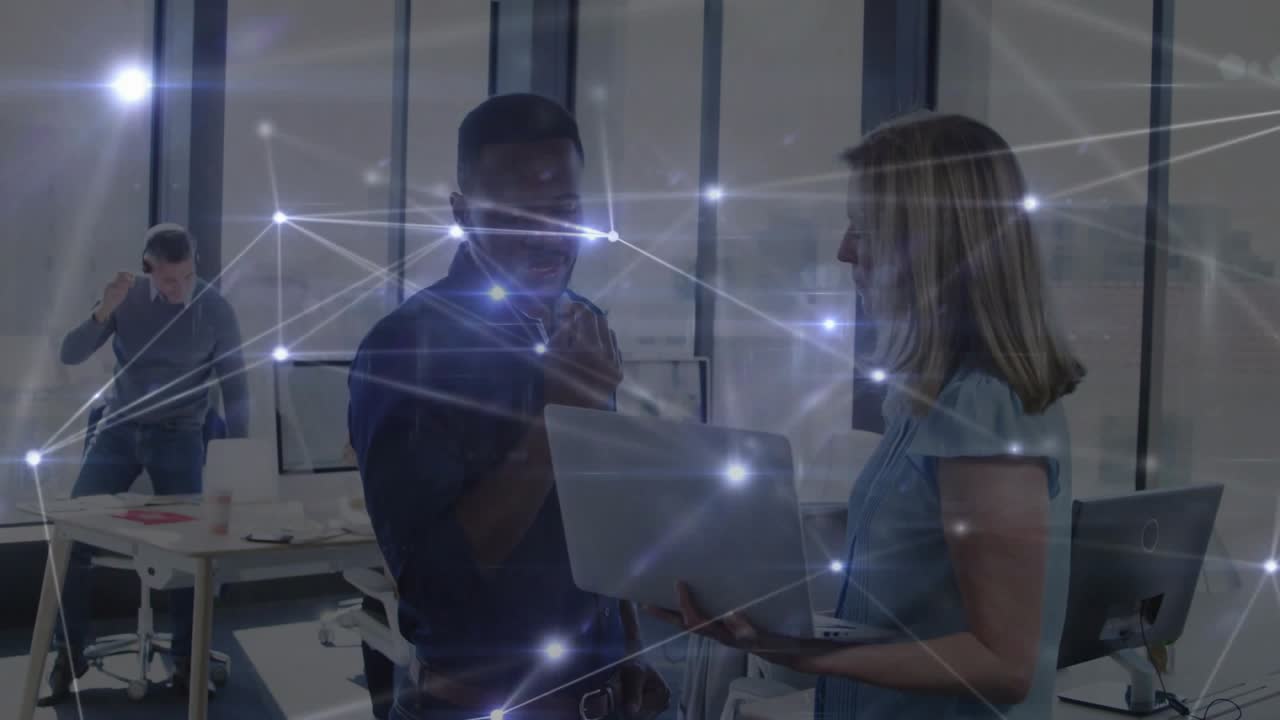 Woman presenting laptop to male office coworker, network overlay rising then fading, duo agreeing