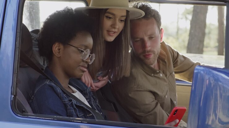 A Young Female Shows The Gps In Her Cellphone To Two Friends Inside The Caravan During A Roadtrip