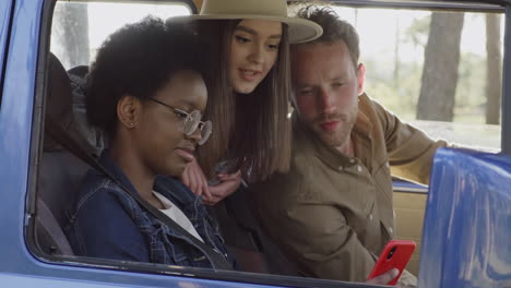 a young female shows the gps in her cellphone to two friends inside the caravan during a roadtrip