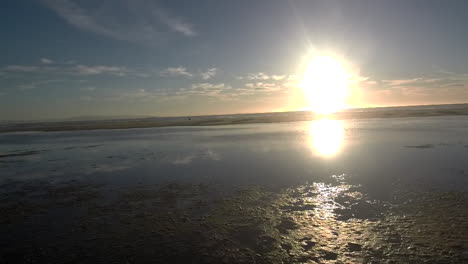 travelling de izquierda a derecha en una playa justo encima de la laguna con la puesta de sol de fondo