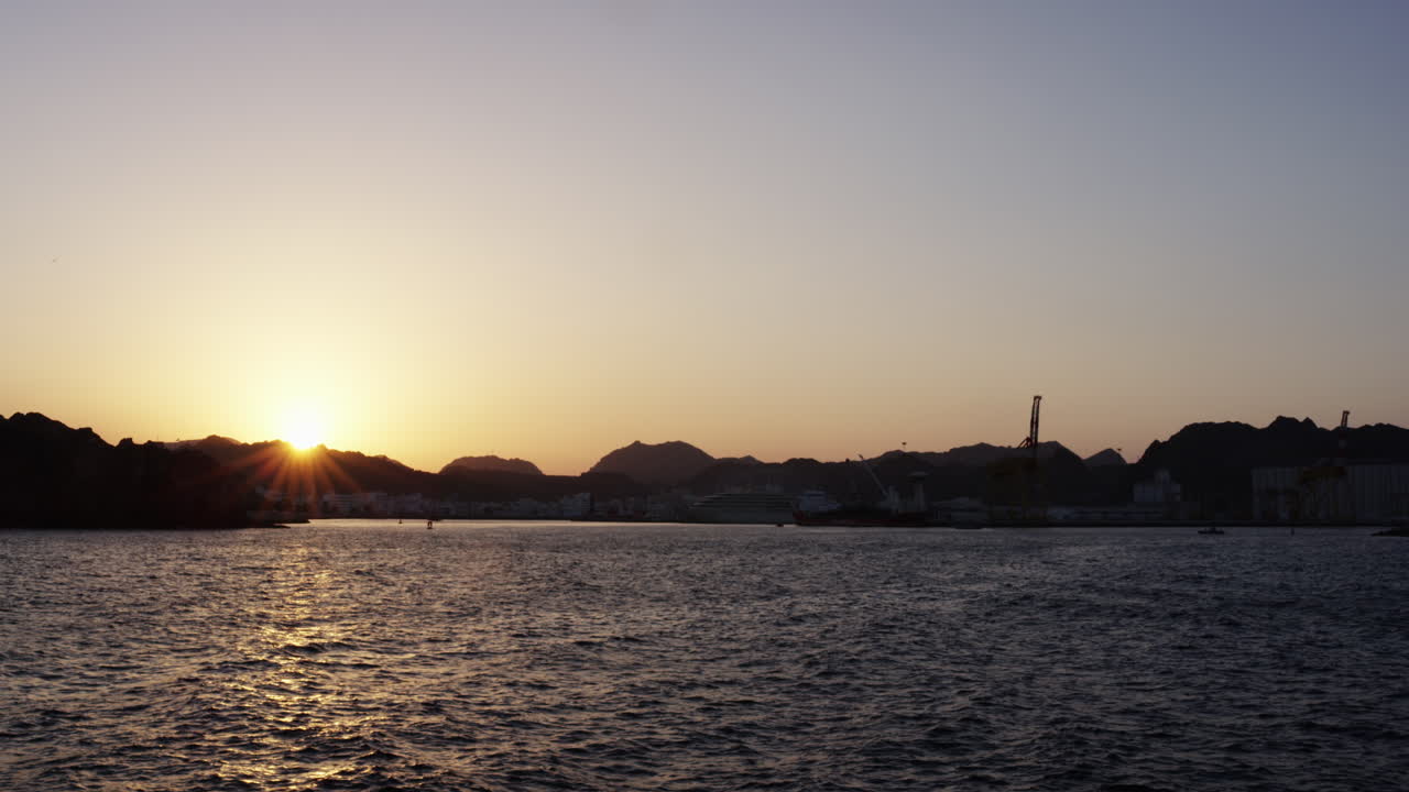 Sunset across the ocean, the hills and mountains of Muscat, Oman, wide shot
