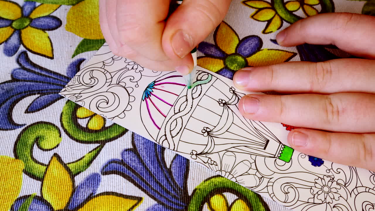 niño joven coloreando diseño detallado de globo de aire caliente con marcadores en mantel floral