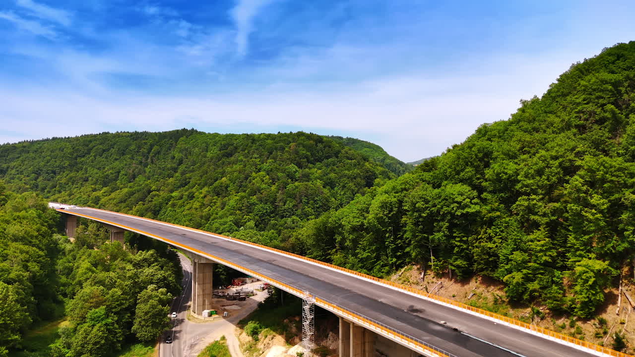 Scenic bridge in lush landscape. Elevated highway curves through dense greenery under a bright blue sky during a sunny day in a mountainous region